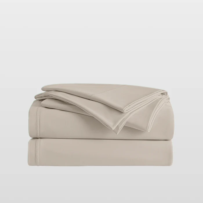 Beige bed sheets folded on a light gray background