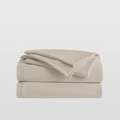 Beige bed sheets folded on a light gray background