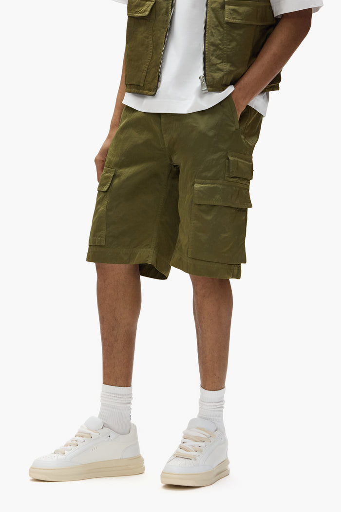 Cargo shorts in green sateen with utility flap pockets and five-pocket design.