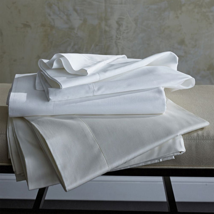 Two flat sheets in classic colors white and ivory folded on a bench.