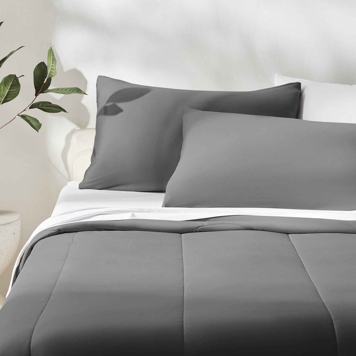 Dark gray cooling pillow shams and cooli ng comforter layered on a neatly made bed
