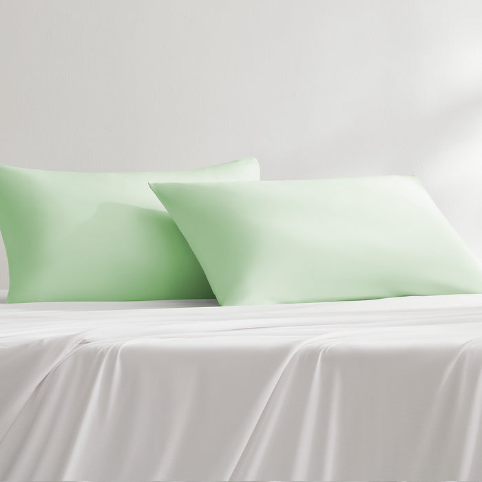 Light green cooling pillowcases styled on a bed with matching bedding