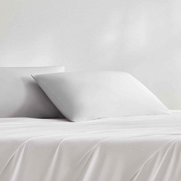 Light gray cooling pillowcases styled on a bed with matching bedding