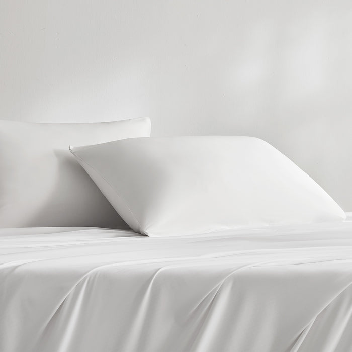 White cooling pillowcases styled on a bed with matching bedding