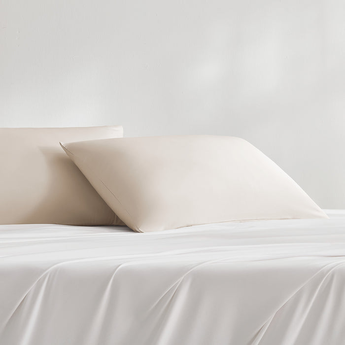 Beige cooling pillowcases styled on a bed with matching bedding