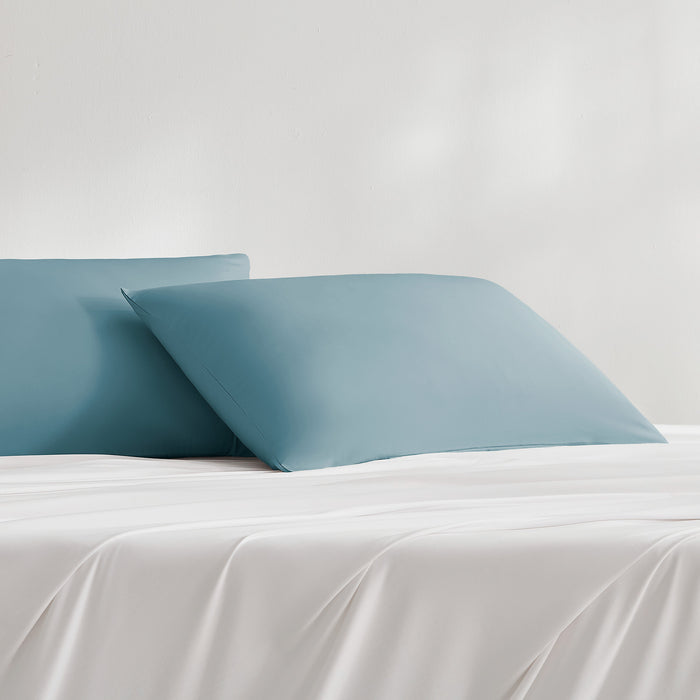 Teal cooling pillowcases styled on a bed with matching bedding