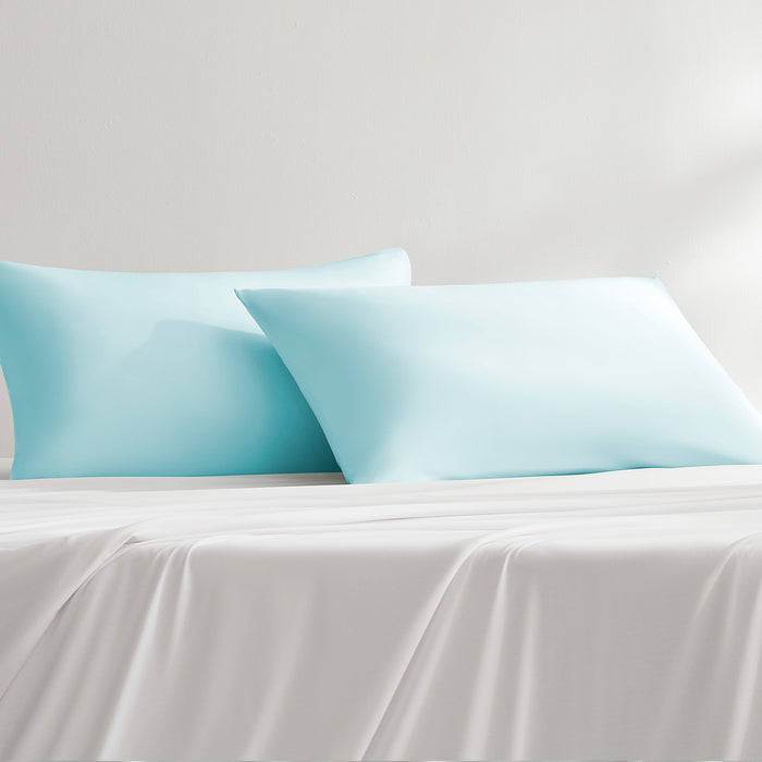 Blue cooling pillowcases styled on a bed with matching bedding