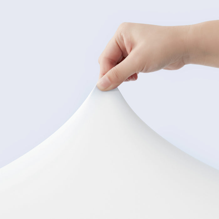 Hand holding a sheet of white cooling fabrics against a light gray background