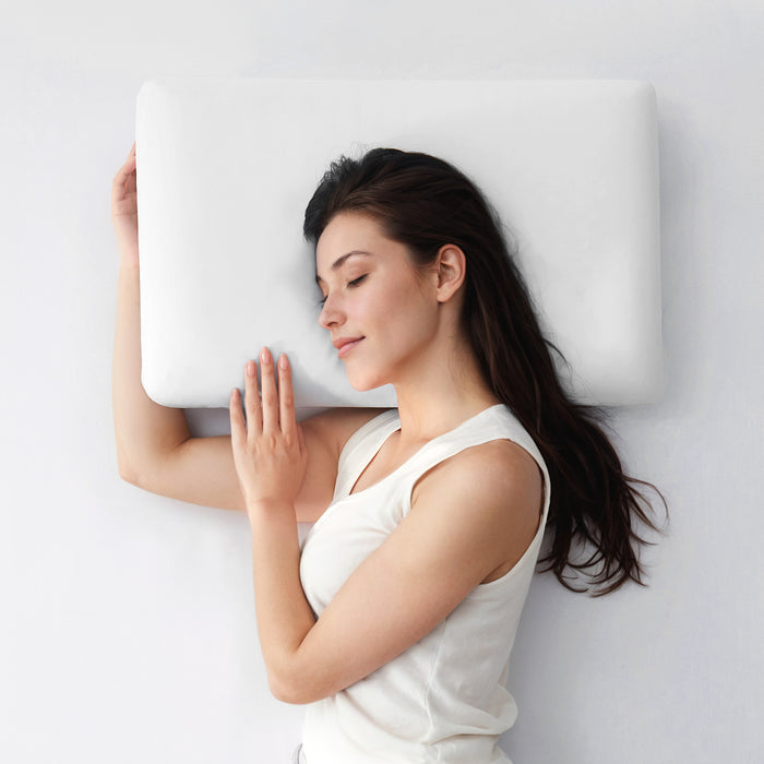 Woman lying on a white cooling pillow against a light gray background