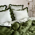 Eucalyptus bedding styled on a bed with scalloped edge pillowcases and smooth fabric in dark green and light green.