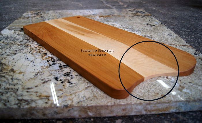 The TY Fine Furniture Mixed Wood Cutting Board with Integrated Bowl Scoop features a scooped end for easy transfer, blending functionality and style in a handcrafted design. A black circle highlights this unique feature on the board.