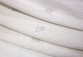 A close-up of the Organic Stretch Mattress Protector by TY Sleep, made from soft organic cotton in cream, with a subtle dotted texture and delicate light brown embroidered leaf motifs.