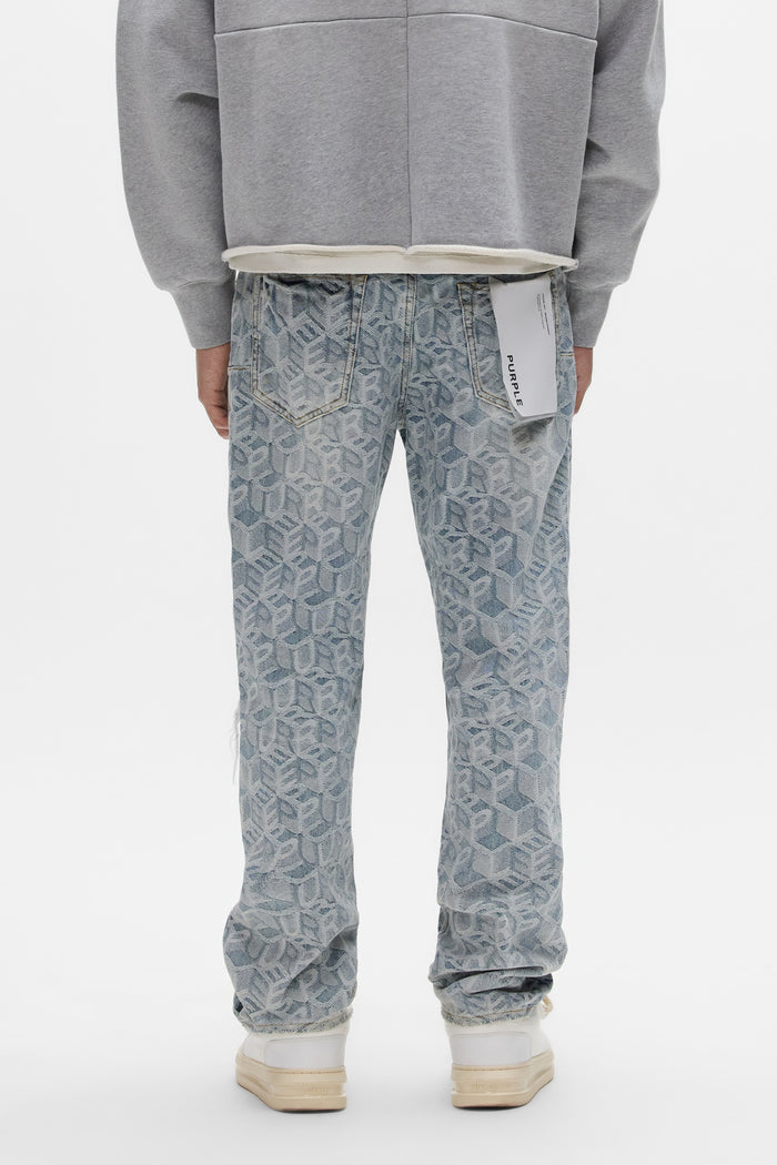 A person faces away wearing PURPLE BRAND P011 Jacquard Monogram light blue mid rise jeans with a white back pocket tag, paired with a grey sweatshirt and white sneakers, set against a plain white background.